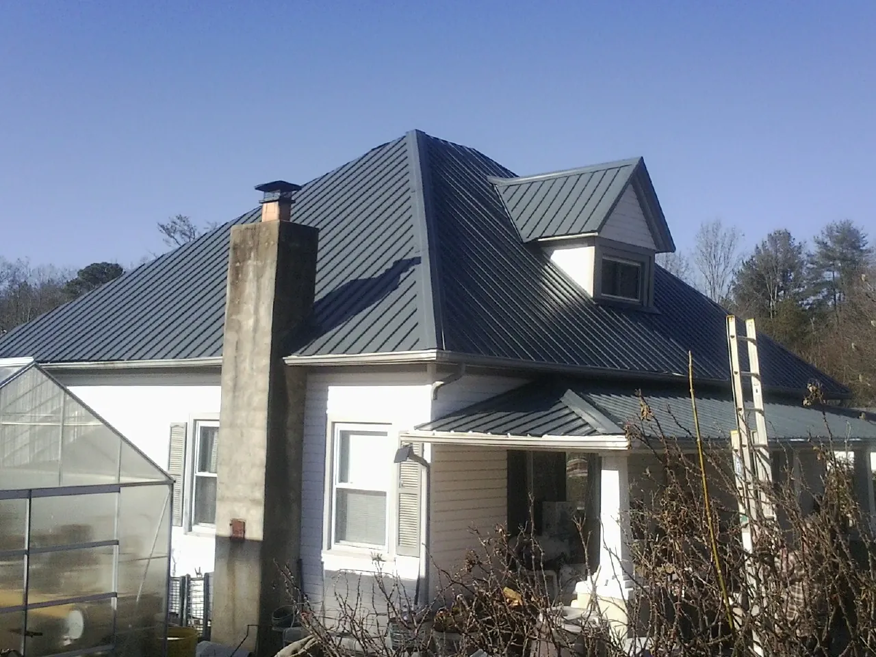 Dark blue standing seam metal roof on a white farmhouse with dormer — Slate & Tile Roof Repair by Roofing Brothers in Lutherville Timonium