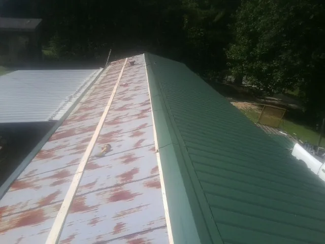 Old rusted panels beside newly installed green metal roofing — Wind Damage Roof Repair by Roofing Brothers in Lutherville Timonium