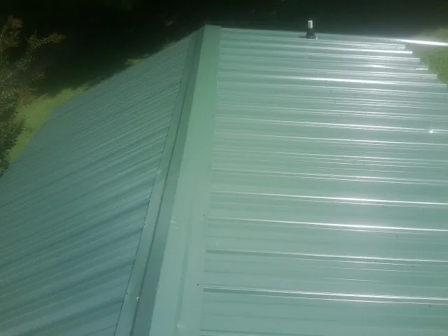 New green metal panels meeting at the ridge of a roof — Flat Roof Repair work by our crew in Lutherville Timonium