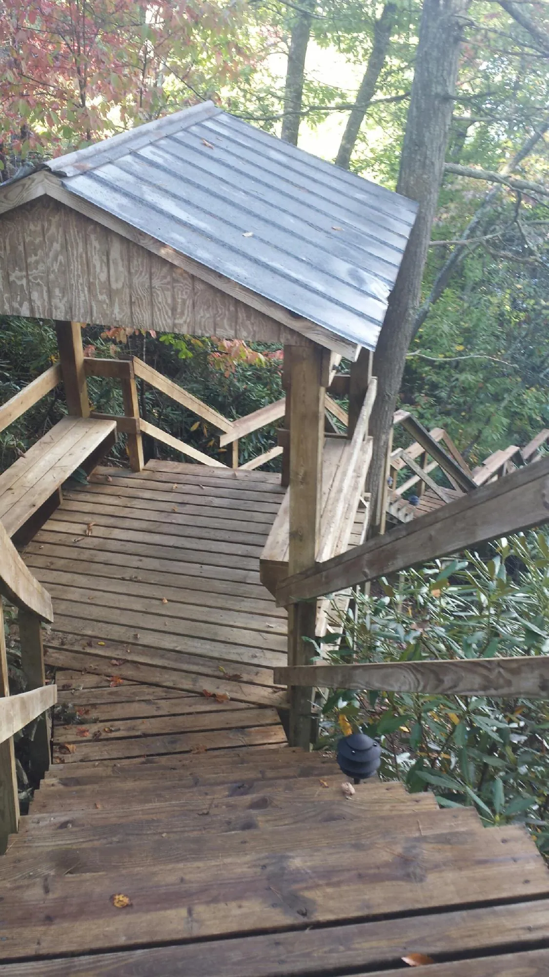 Metal roofed shelter over wooden steps on a wooded walkway — Skylight Repair & Installation work by our crew in Lutherville Timonium