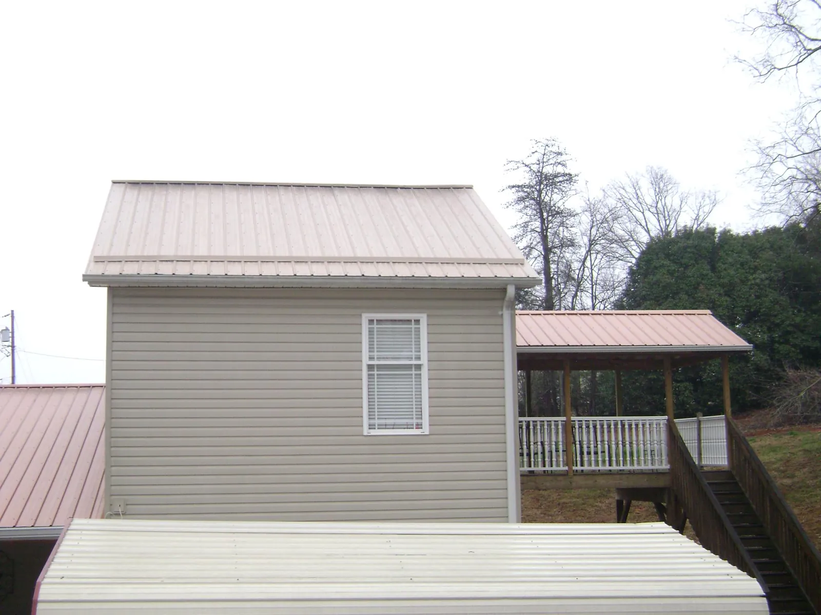 Tan metal roofs on a two story addition and attached porch, from a Roof Replacement job in Lutherville Timonium